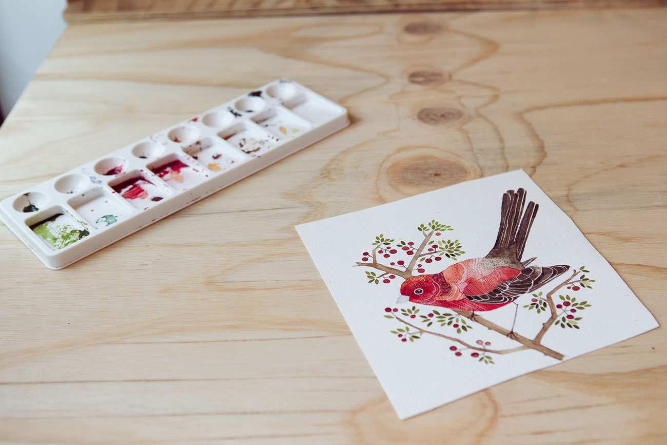 artists watercolour paints and painting of a bird on the desk