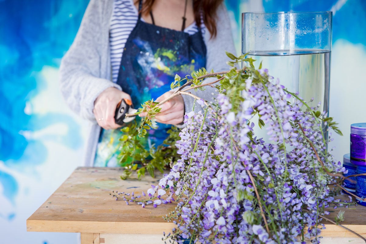 artist trimming purple flowers to put in vase