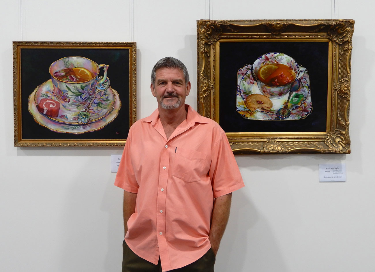 artist in front of works in gallery