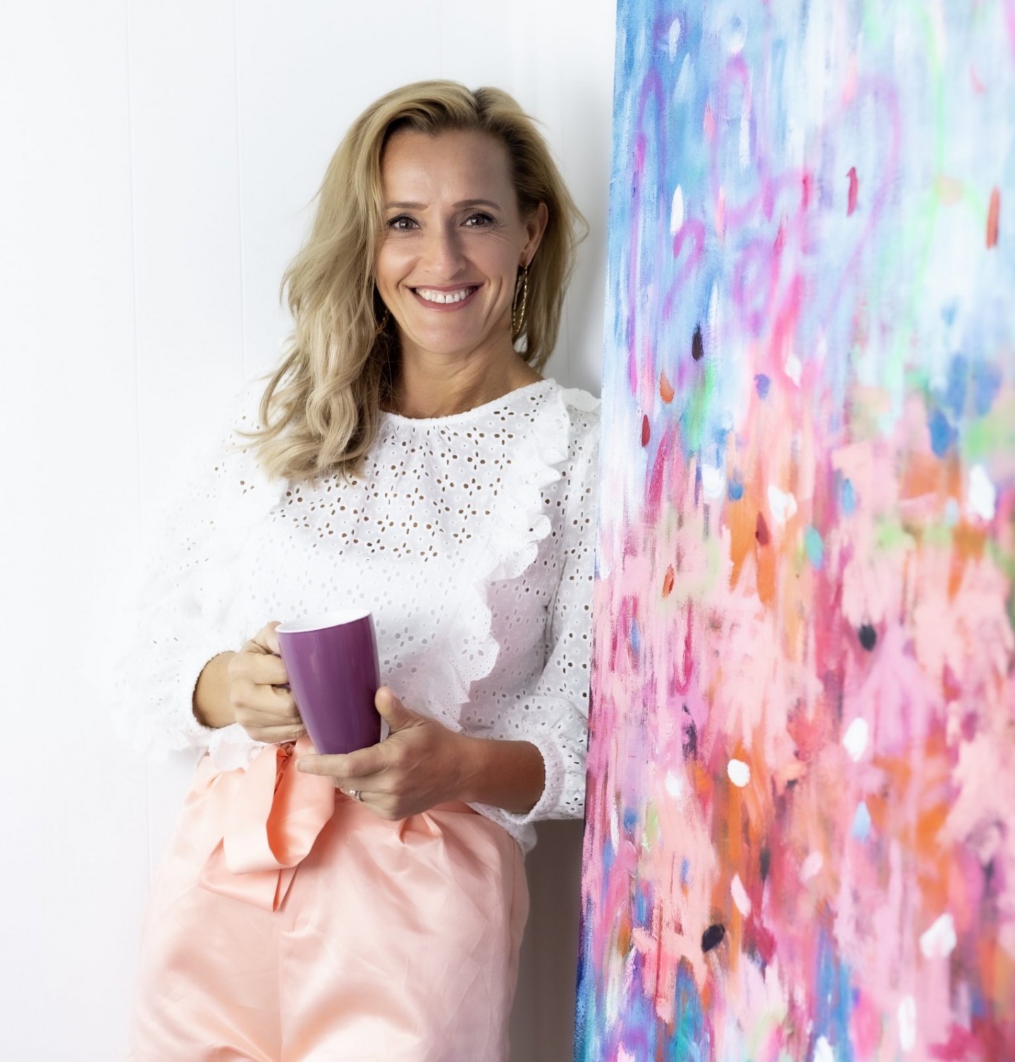 Local Sydney abstract artist Belinda Nadwie with a pink and blue artwork and coffee mug.