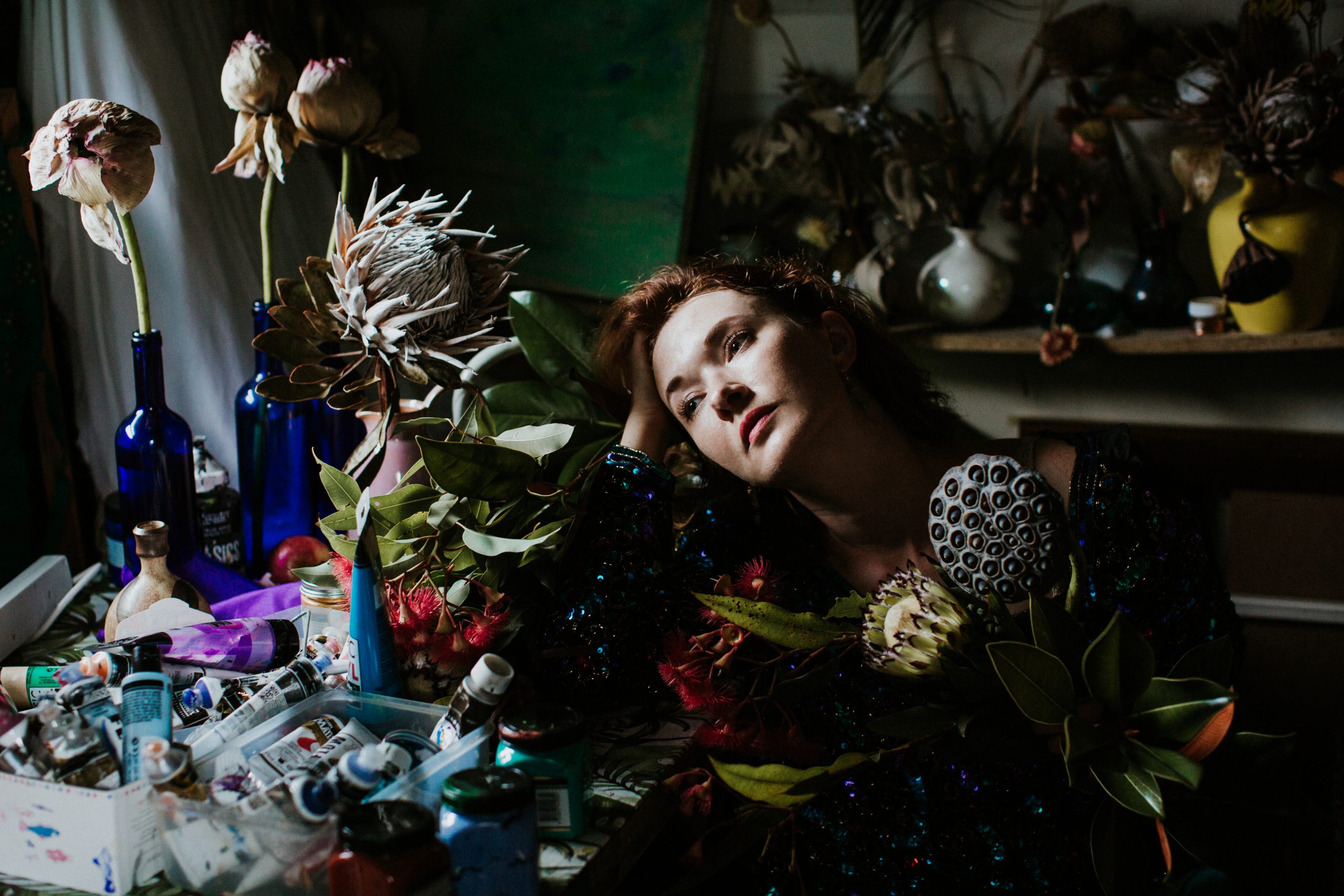 Katerina Apale surrounded by flowers and paintings