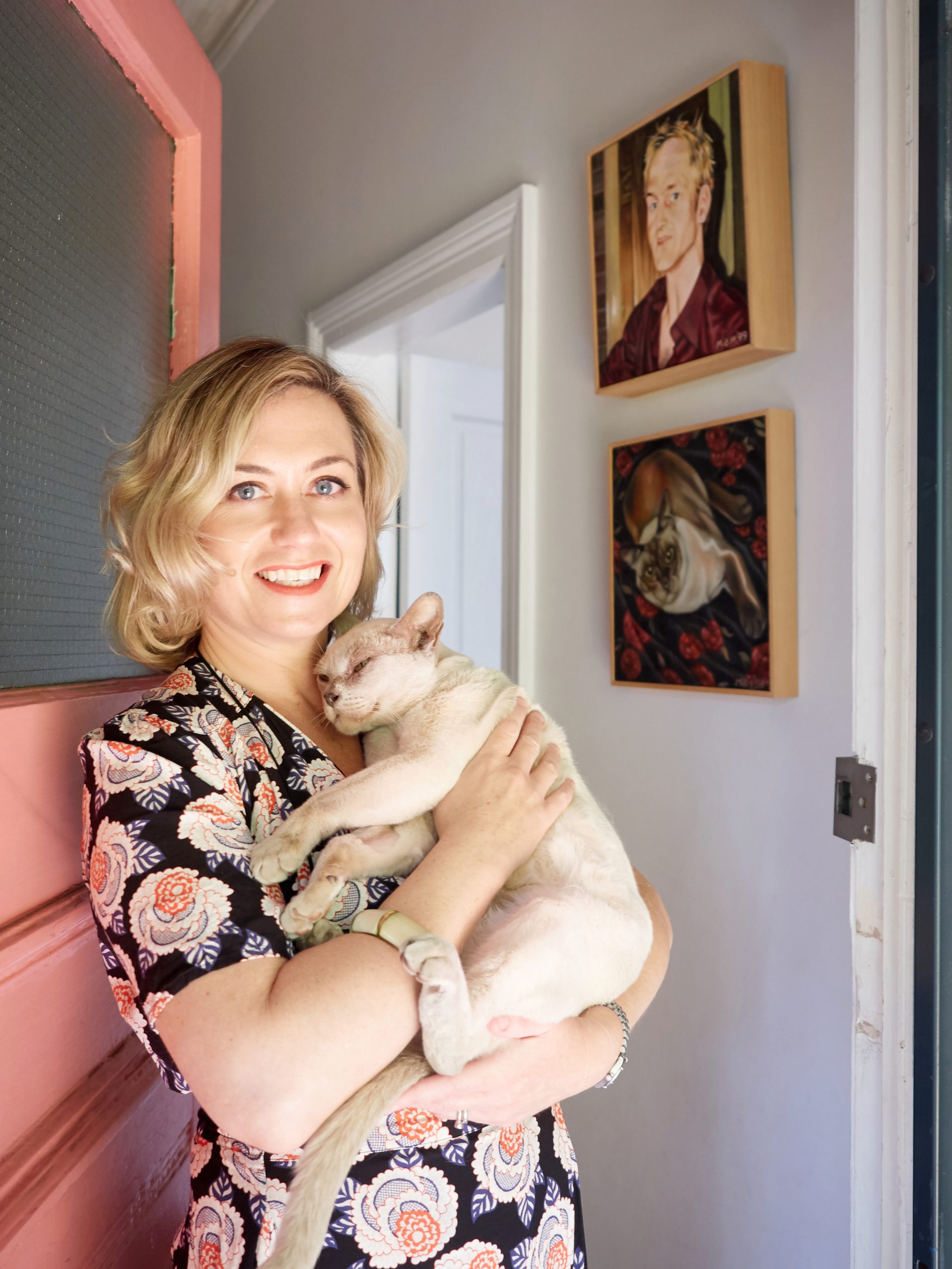 Sally in front of her millenium pink front door holding Rupert the cat