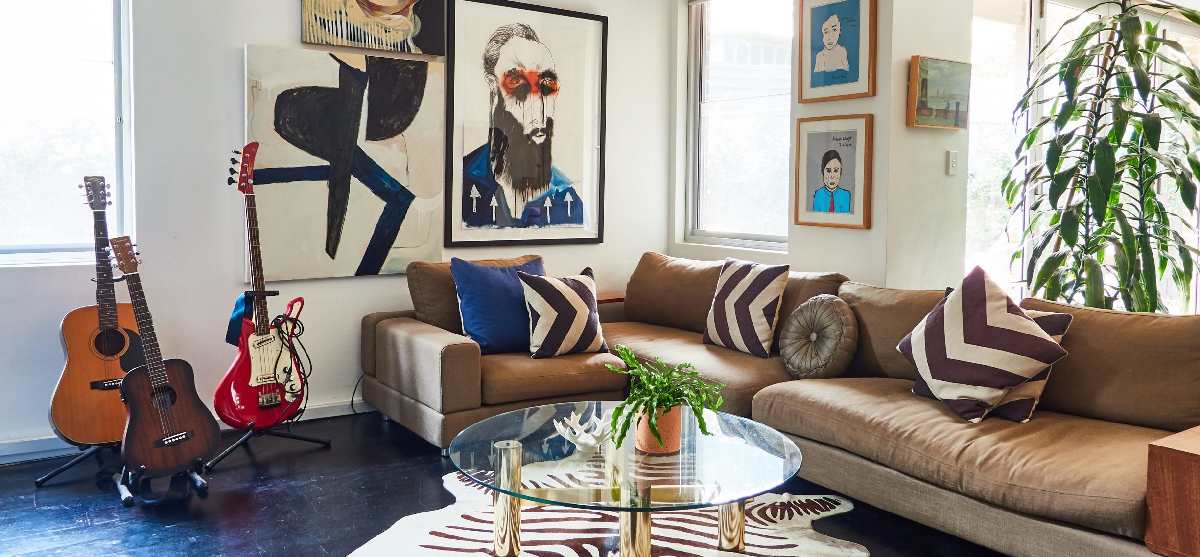 Eclectic living room with guitars, animal rug, plant and multiple artworks