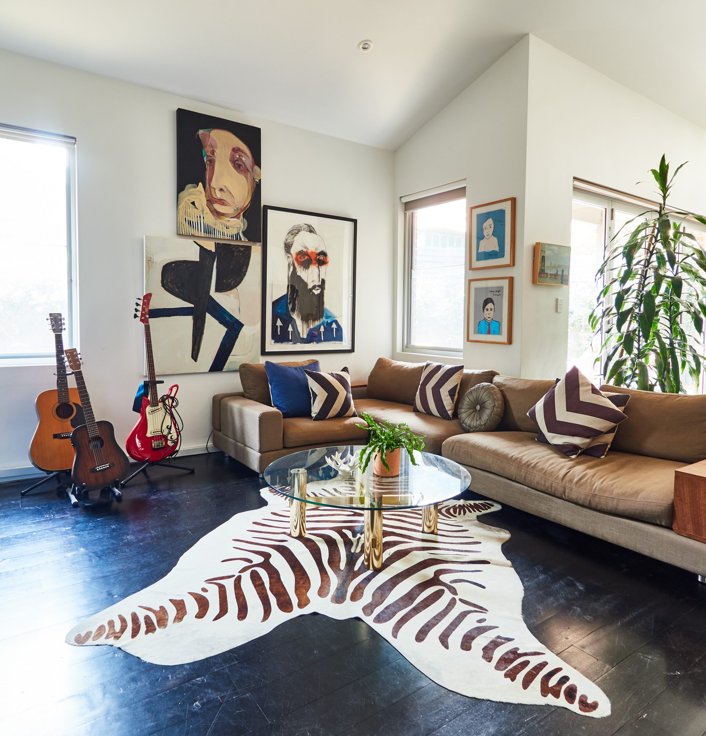 Eclectic living room with guitars, animal rug, plant and multiple artworks