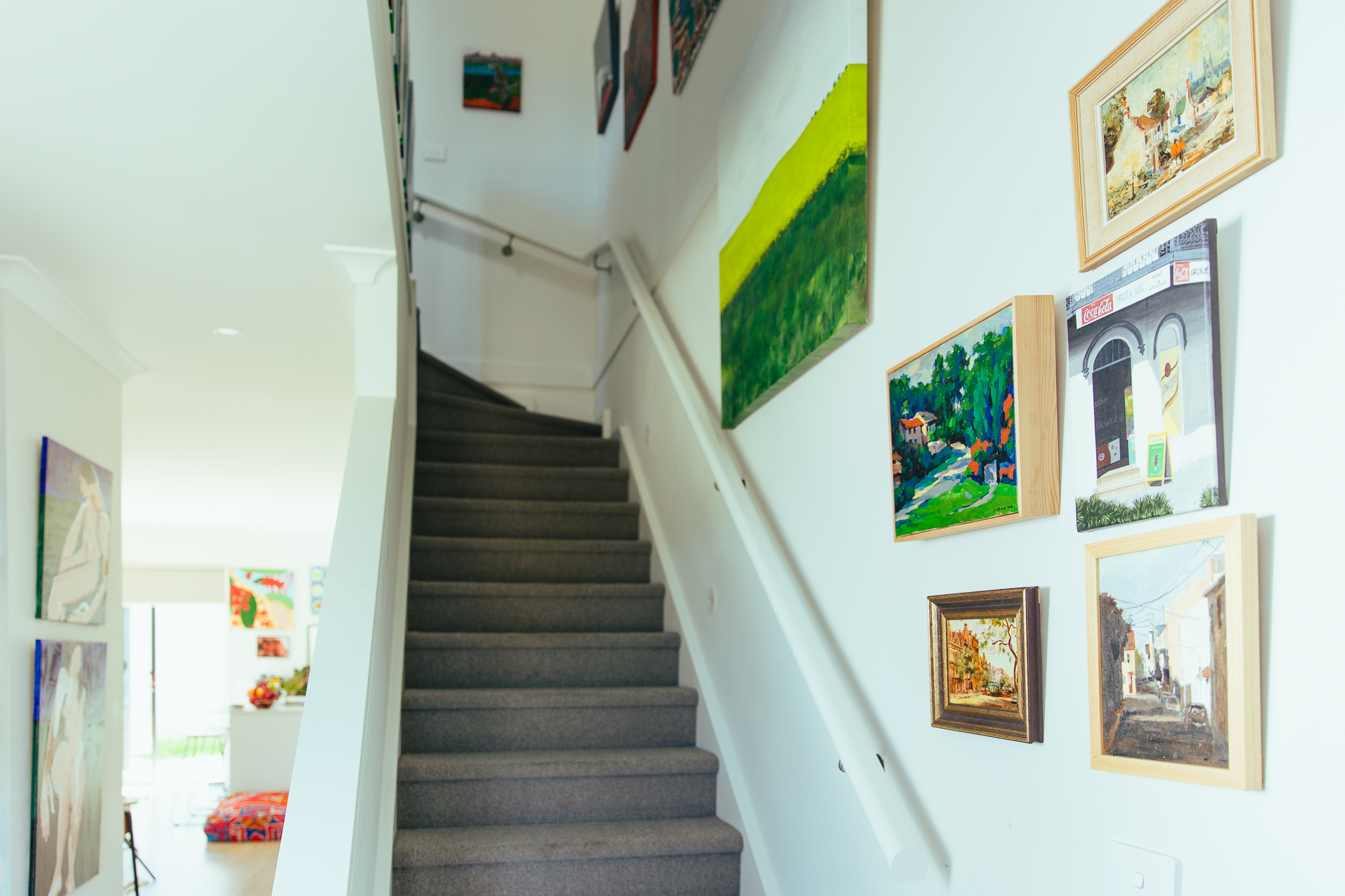 Hallway and staircase with multiple small artworks hung gallery style