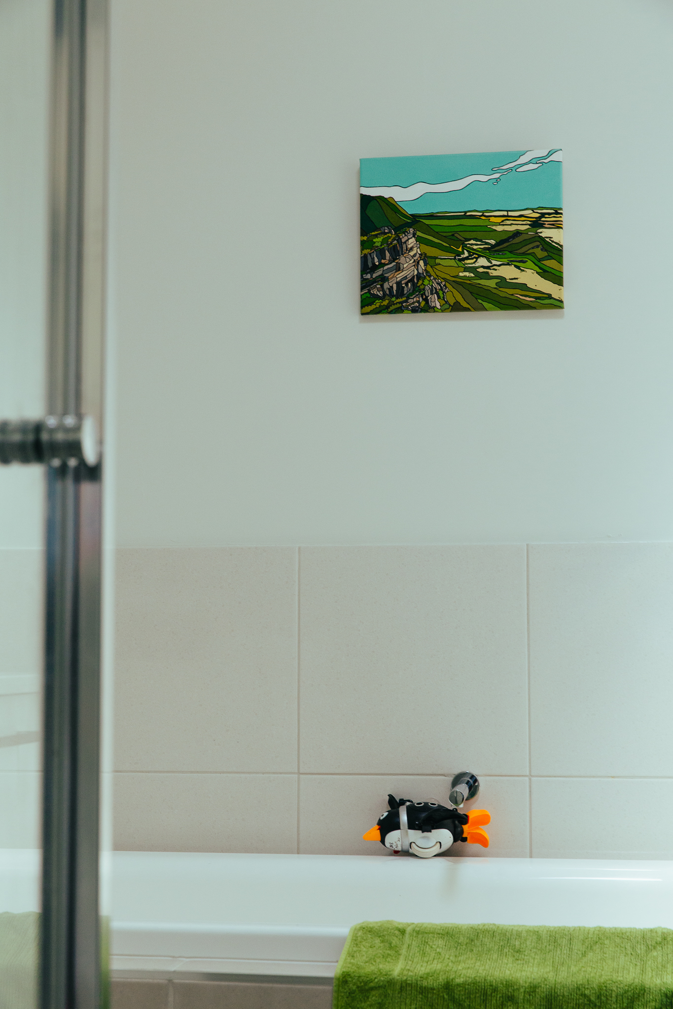 green landscape artwork in bathroom with green towel and rubber duck