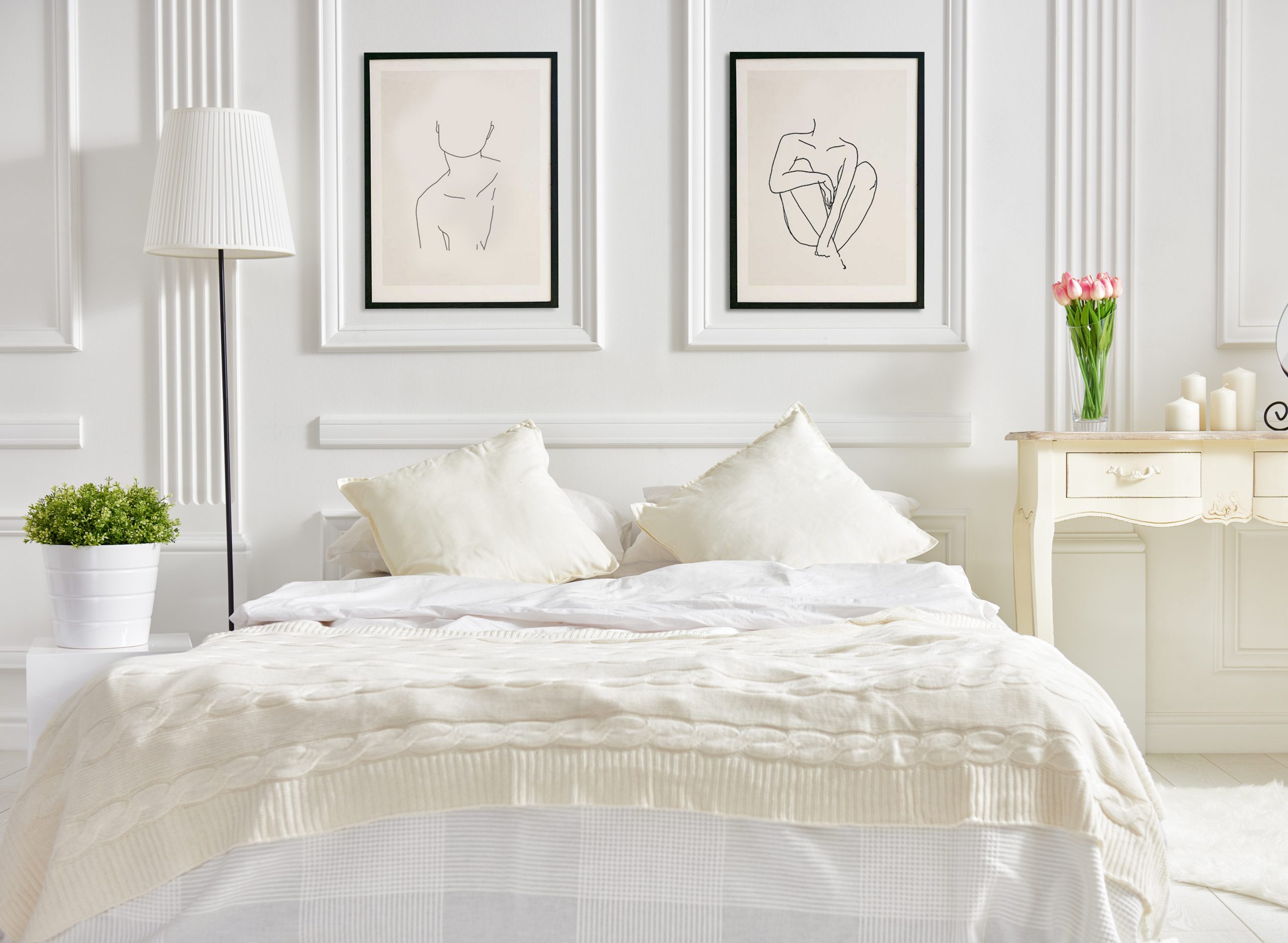 two fine art prints of figurative line drawings above a bed