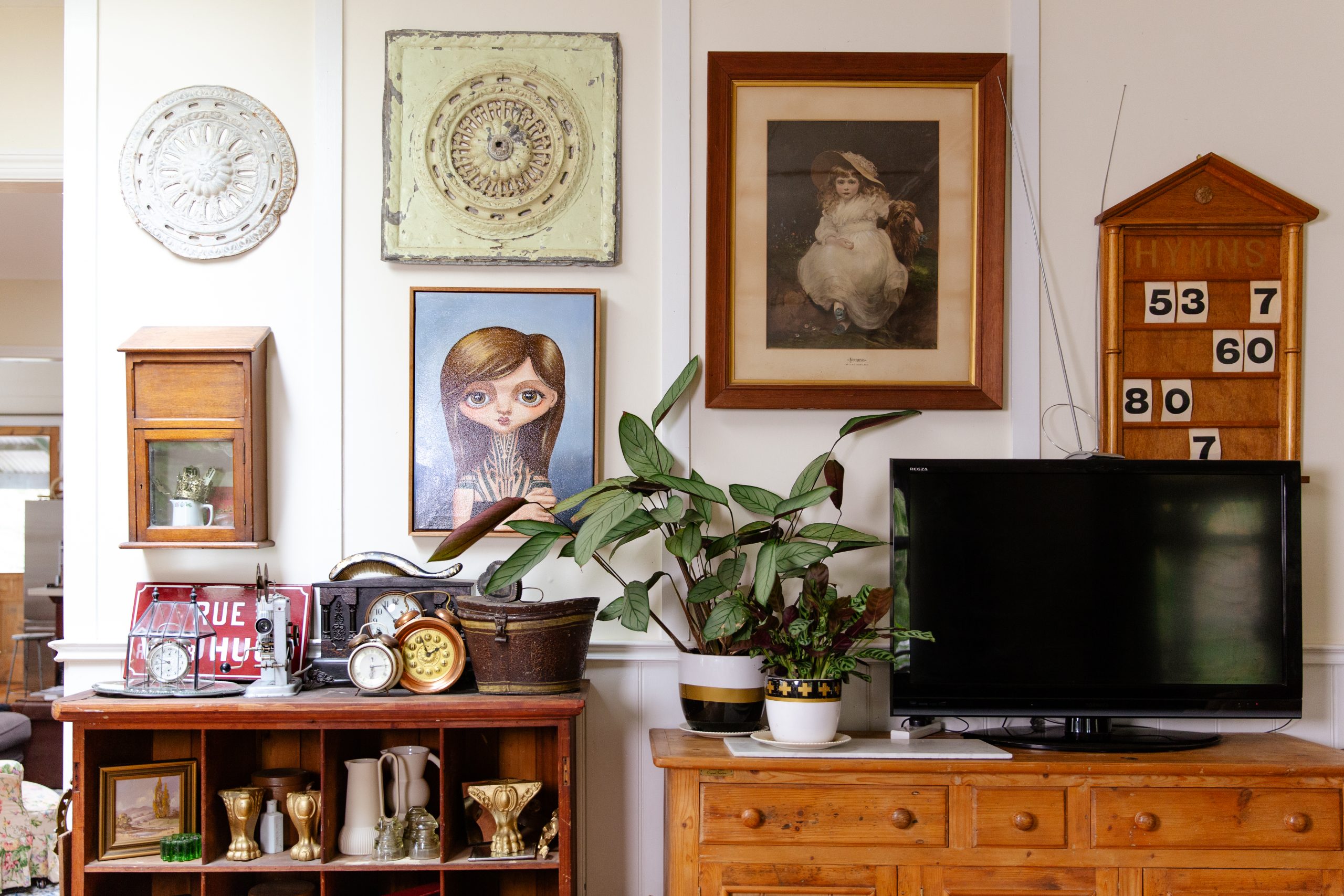 A room in Alicia's home with artwork on the wall and furniture covered with antique items.
